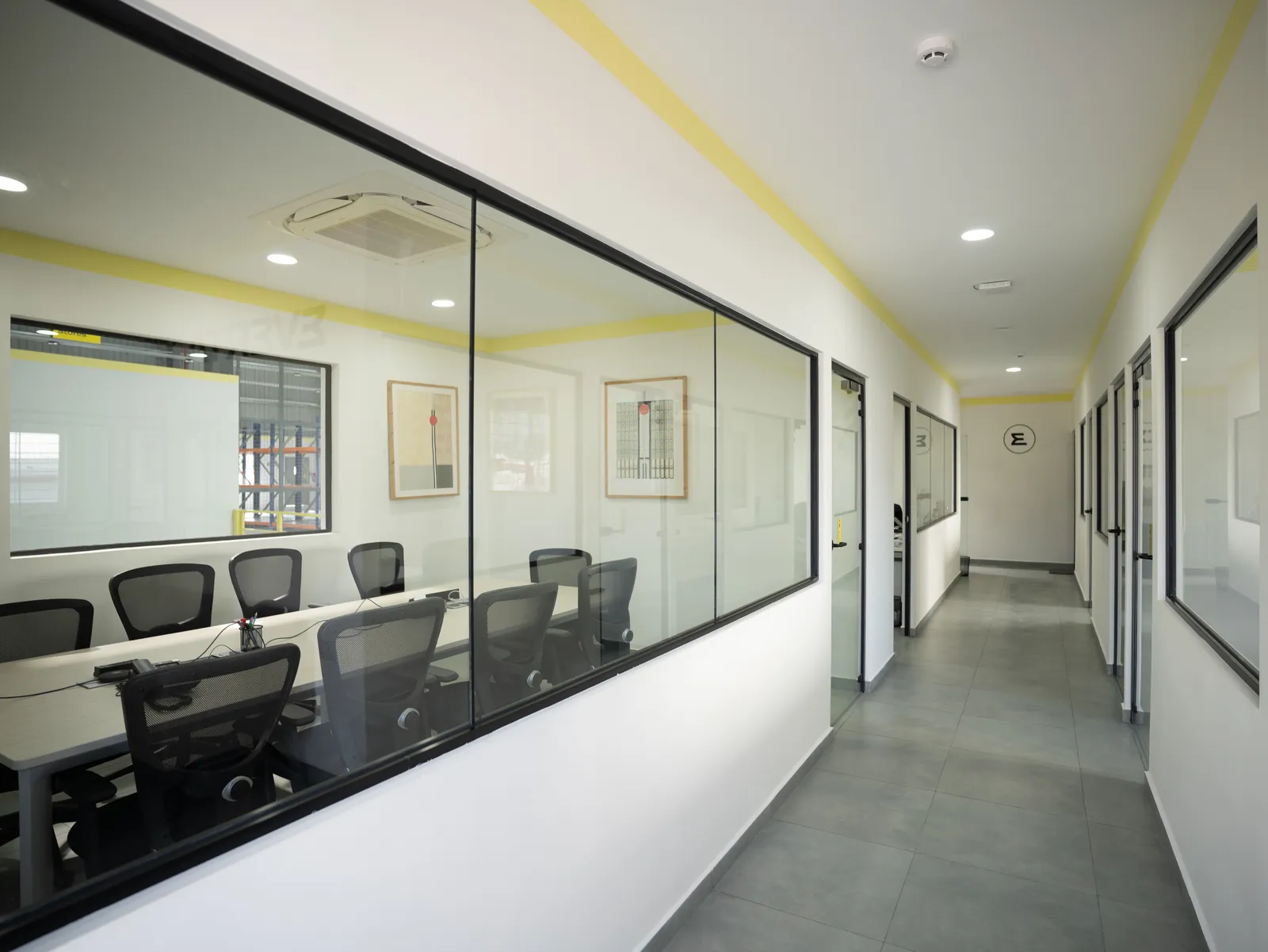 Glass-walled meeting room and office corridor — Everta